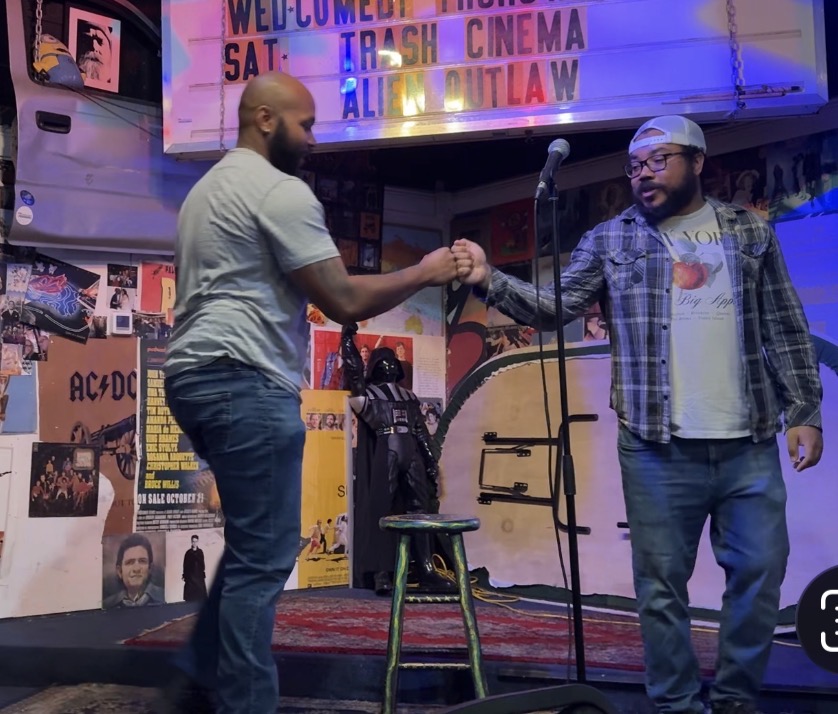 AJ Frazier greeting another comedian beside the microphone